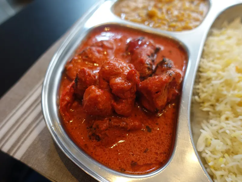 Chicken tikka masala in a metal tray next to rice