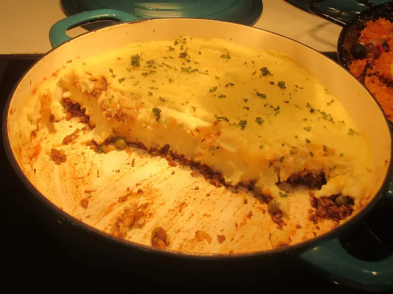 Cottage pie in an orange casserole dish, the mash browned on top