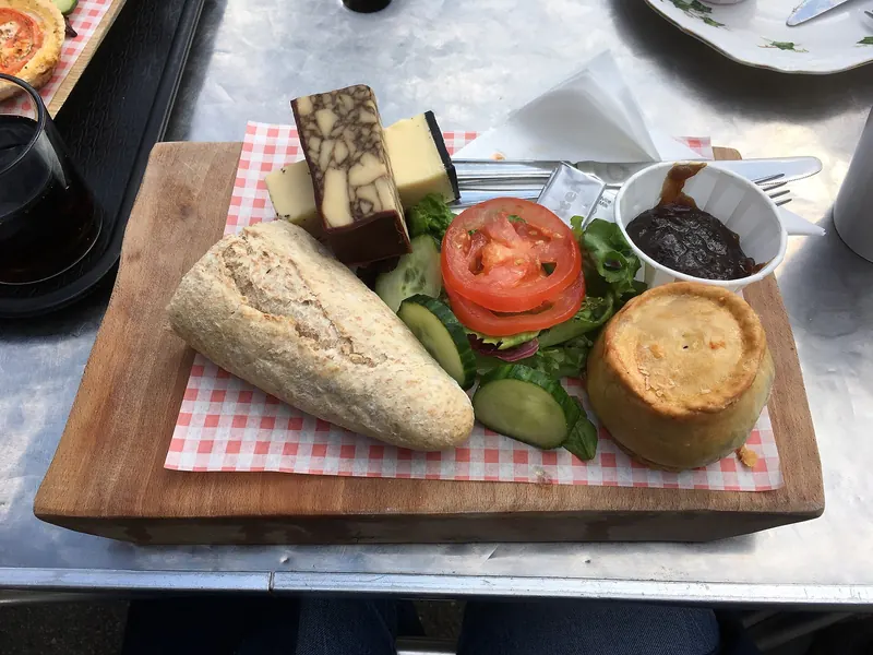 Ploughman's lunch on a board: cheese, bread, pickle and salad