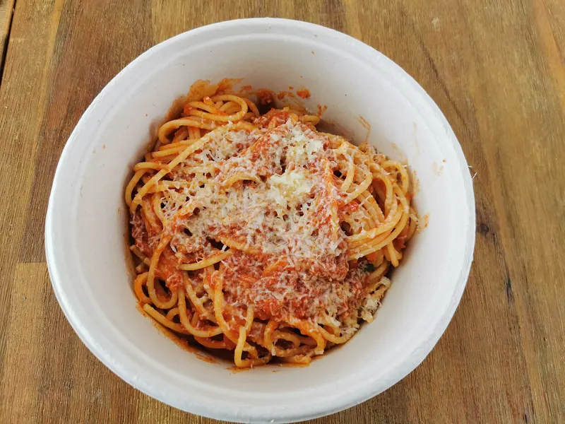 Spaghetti bolognese with grated cheese in a white bowl
