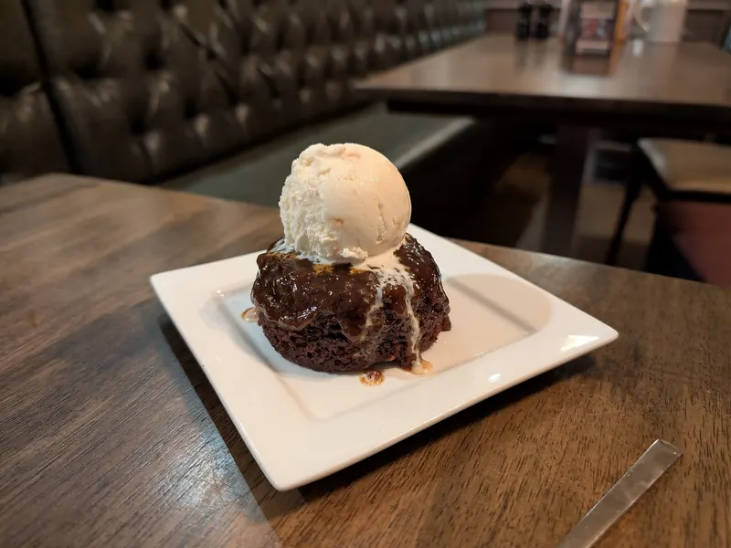 Sticky toffee pudding with ice cream on a white plate